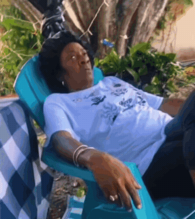 Woman Laying In Blue Chair In Garden GIF