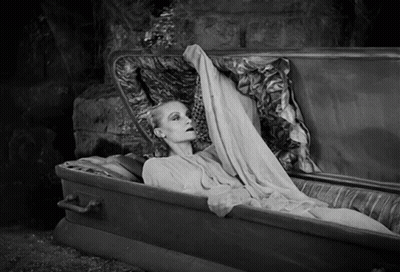 Woman Laying In Coffin Holding Blanket Over Head GIF