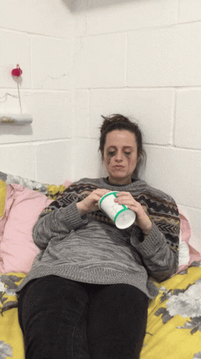 Woman Laying On Bed Holding Iced Tea Cup GIF