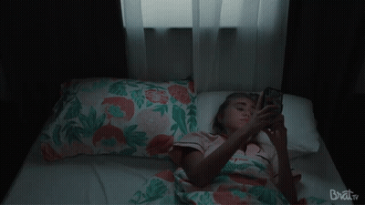 Woman Laying On Bed Looking At Phone Brat TV GIF