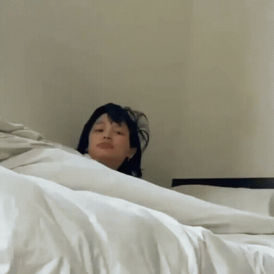 Woman Laying On Bed Making Funny Face GIF