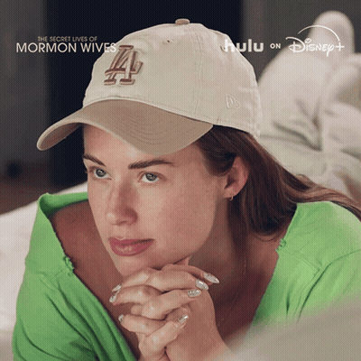 Woman Laying On Bed Wearing Hat Saying La GIF