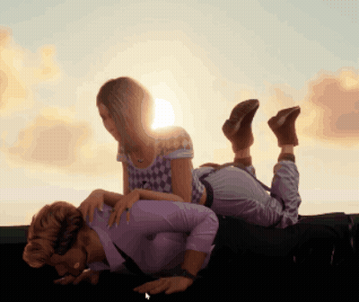 Woman Laying On Man's Lap With Sun Behind Them GIF