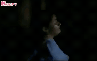 Woman Leaning Against Pole In Dark GIF