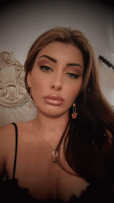 Woman Looking At Camera In Black Tank Top And Butterfly Earrings GIF