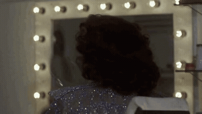 Woman Looking At Herself In Mirror With Lights GIF