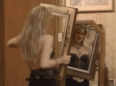 Woman Looking At Self In Mirror Holding Picture Frame GIF