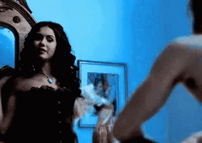 Woman Looking In Mirror With Man Standing Next To Her GIF