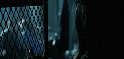 Woman Looking Out Of Wire Fence At Crowd GIF
