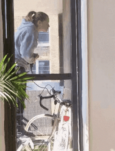 Woman Looking Out Window At Bike GIF