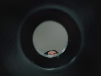 Woman Looking Through Hole In Wall GIF