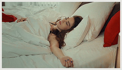 Woman Lying On Bed With White Sheets And Red Pillows GIF