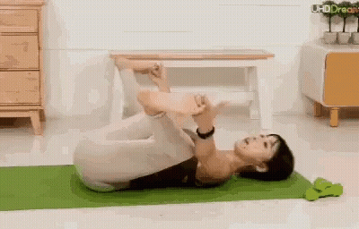 Woman Lying On Yoga Mat Legs Crossed Dumbbell GIF