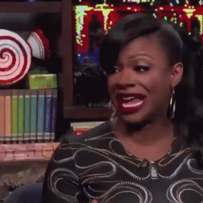 Woman Making Funny Face At Bookshelf With Lollipops GIF