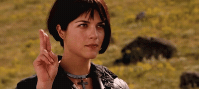 Woman Making Peace Sign In A Field Of Flowers GIF