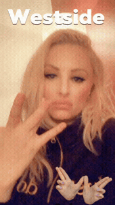 Woman Making Peace Sign In Front Of Westside Sign GIF