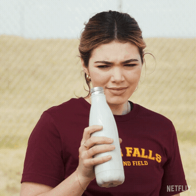 Woman Maroon Falls-And-Field Shirt Holding Milk Bottle GIF