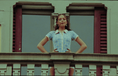 Woman On Balcony With Hands On Hips Looking Out Window GIF