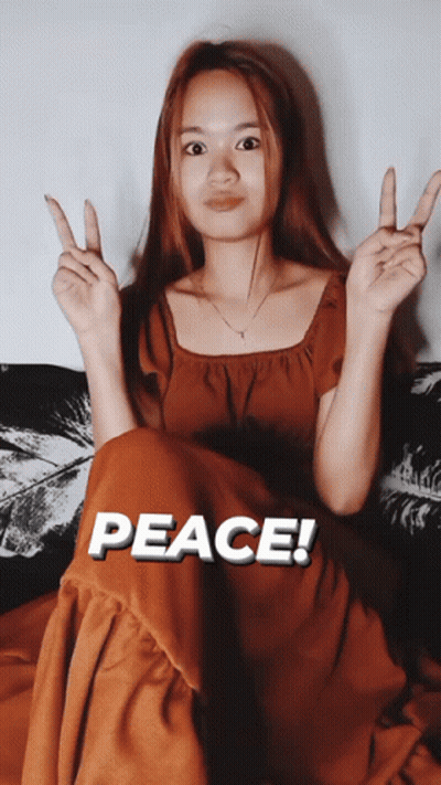 Woman On Couch Giving Peace Sign Saying Peace GIF