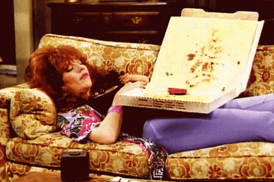Woman On Couch Holding Pizza Box Saying LS GIF