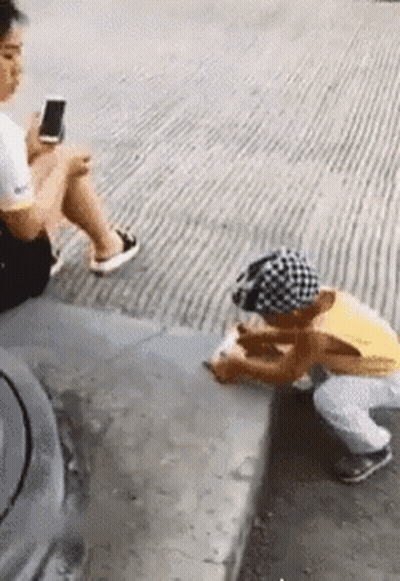 Woman On Phone Child Squatting On Sidewalk GIF