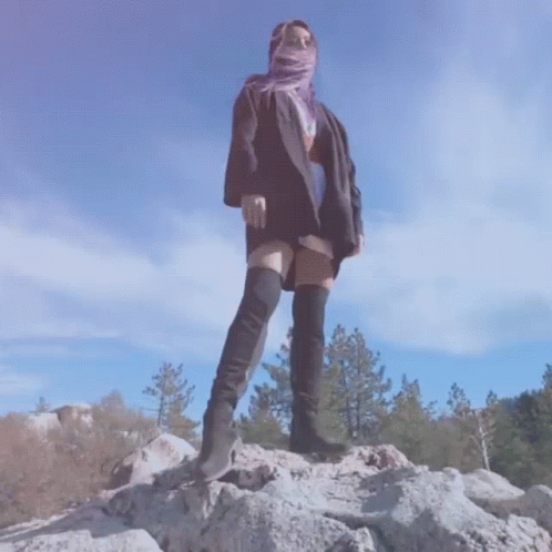 Woman On Rock In Thigh High Boots And Scarf GIF