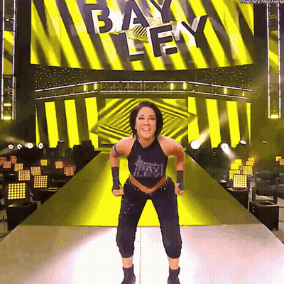 Woman On Stage In Front Of Bayley Screen GIF