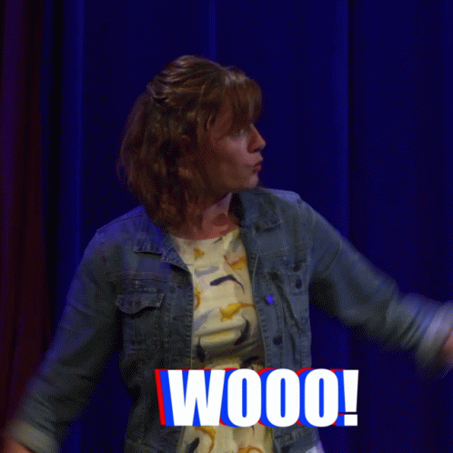 Woman On Stage With Arms Up Saying Fireworks GIF