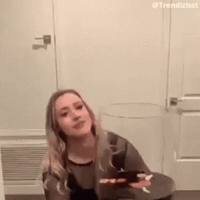 Woman On Stool By Door Looking At Camera GIF