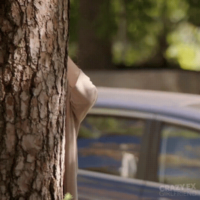 Woman Peeking Behind Tree GIF