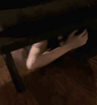 Woman Peeking From Under Couch With Hand Reaching Out GIF