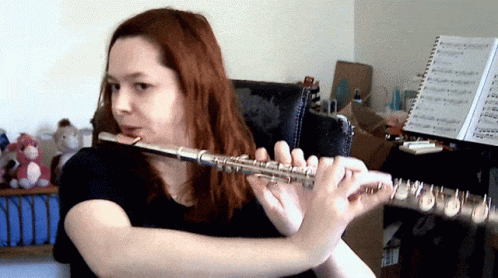 Woman Playing Flute At Sheet Music Stand GIF