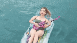 Woman Playing Guitar In Center Of The Pool GIF