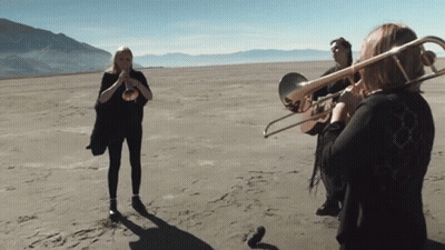 Woman Playing Trombone In Desert GIF