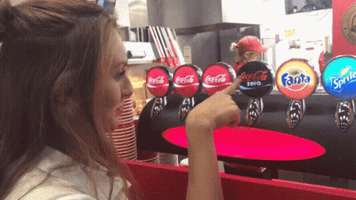 Woman Pointing At Coca Cola Sprite And Fanta Dispenser GIF