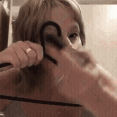 Woman Putting Hanger On Face GIF