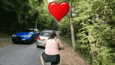 Woman Riding Bike Past Blue Car GIF