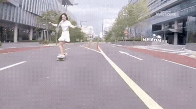 Woman Riding Skateboard Past Nexon Sign GIF