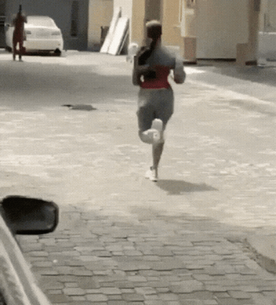 Woman Running Down Cobblestone Street With Car GIF