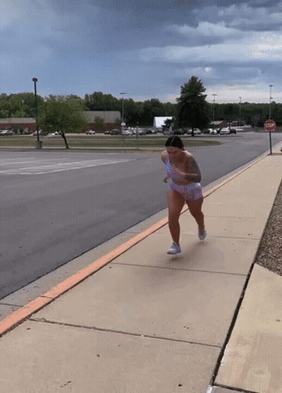 Woman Running Down Sidewalk With Stop Sign GIF