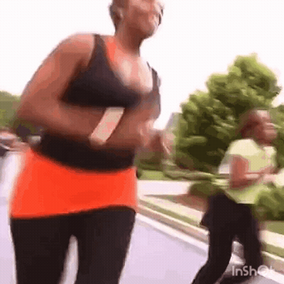 Woman Running Down Street In Black Tank Top And Orange Skirt GIF