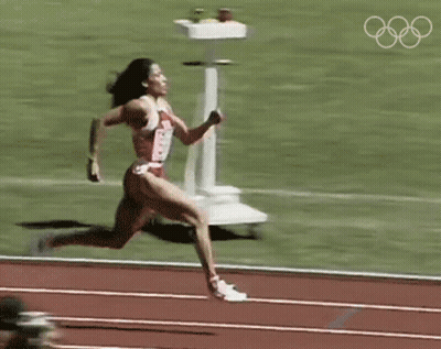 Woman Running On Track With Olympic Rings GIF
