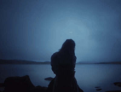 Woman Silhouette Standing On Rock Near Water GIF