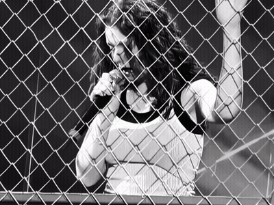 Woman Singing Behind Chain Link Fence With Letter C GIF