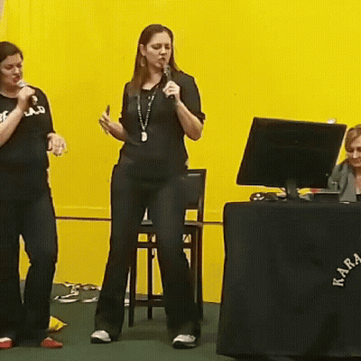 Woman Singing Into Microphone At Akra Table GIF