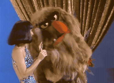 Woman Singing Into Microphone Beside Eagle Puppet GIF