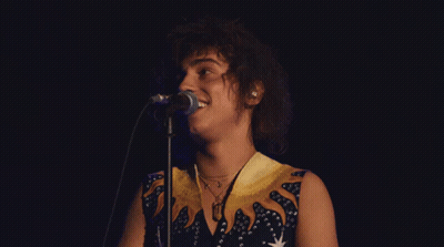 Woman Singing Into Microphone In Blue And Yellow Dress GIF