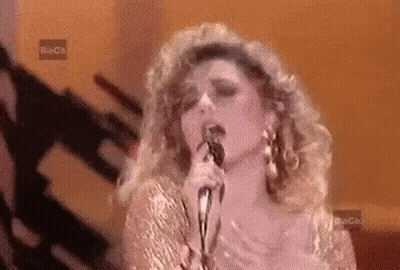 Woman Singing Into Microphone In Front Of Beca Sign GIF