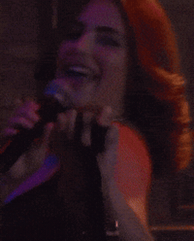 Woman Singing Into Microphone In Front Of Boston Sign GIF