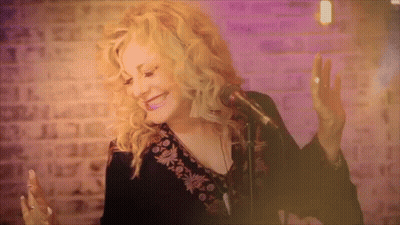 Woman Singing Into Microphone In Front Of Brick Wall GIF